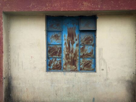 Vintage old window in an ancient cement and brick wall of an abandoned house. An outside window wall with paint peeling and damaged.の写真素材
