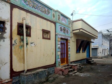 Perspective shot of a beautiful house entrance door in an Indian village, Solapur, India. An entrance is made out of cement structure with fresh vibrant colours and rangoli in front of a home.の写真素材