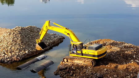 Strong yellow excavator machine works at riverの写真素材