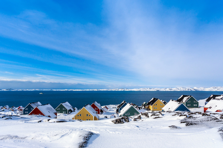 Yellow, blue, red and green inuit houses covered in snow at the fjord of Nuuk city, Greenlandの写真素材
