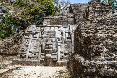 Old ancient stone Mayan pre-columbian civilization pyramid with carved face and ornament hidden in the forest, Lamanai archeological site, Orange Walk District, Belizeの写真素材