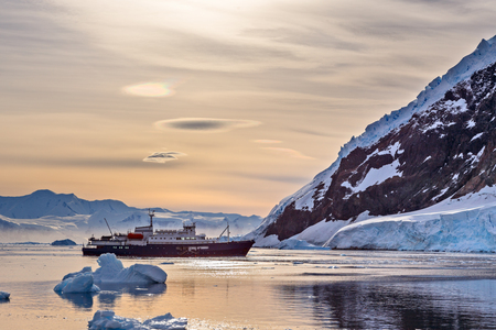 Touristic antarctic cruise vessel among the icebergs with glacier in background, Neco bay, Antarcticaの写真素材