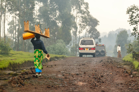 Rwandan woman in colorful traditional cloth walikung and carrying bench on her head, Kigali, Rwandaの写真素材