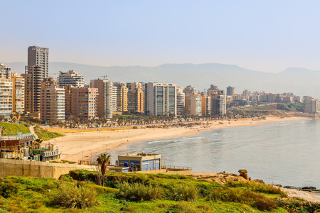 Downtown buildings and towers with road, sandy beach and sea in the foreground, Beirut, Lebanonの写真素材
