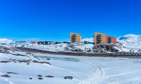 Inuit multistory houses of Nuuk city on the rocks with mountains in the background, Greenland