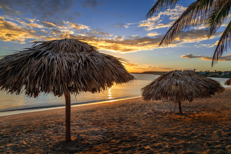 Rancho Luna caribbean beach with palms and straw umbrellas on the shore, sunset view, Cienfuegos, Cubaの写真素材