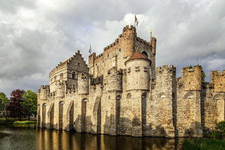 Fortified walls and towers of Gravensteen medieval castle with moat in the foreground, Ghent East Flanders, Belgiumのeditorial素材