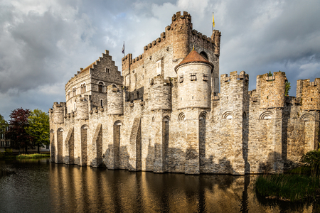 Fortified walls and towers of Gravensteen medieval castle with moat in the foreground, Ghent East Flanders, Belgiumのeditorial素材