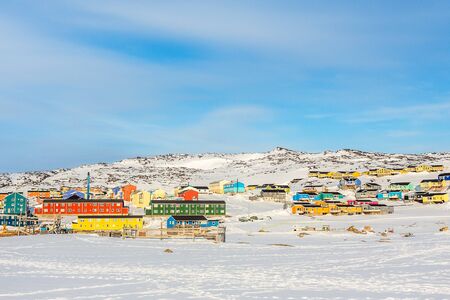 Arctic city center with colorful Inuit houses on the rocky hills covered in snow, Ilulissat,...