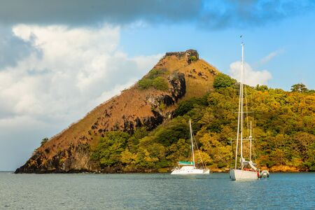 Yachts anchored at the Pigeon Island with fort ruin on the rock, Rodney bay, Saint Lucia, Caribbean...