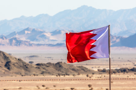 Bahrain flag waving on the wind in Saudi Arabian desertwith mountains in background, Al Ula, Saudi Arabiaの写真素材