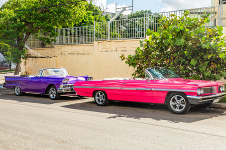 Old american pink and violet retro luxury cars parked in the center of old Havana, Cubaの写真素材