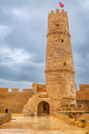 Inner yards and watch tower with tunisian flag on the top of Ribat of Monastir under cloudy skies, Monastir, Monastir Governorate, Tunisiaの写真素材