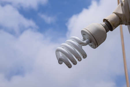 Picture of Installed white CFL bulb on cloudy blue sky background.eco ,energy saving bulb.