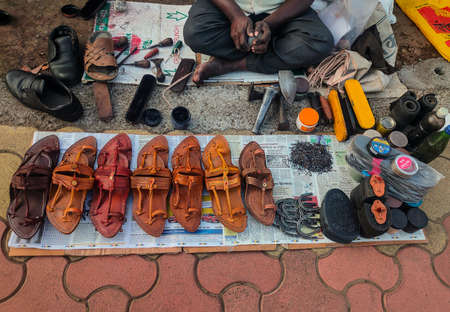 Kolhapur, Maharashtra, India- December 5th 2020;Stock photo of local Indian cobbler shop or shoe repair shop. There are number of traditional handmade chappal and shoe repair tool like leather, thread, cutter, brush, stand etc.のeditorial素材