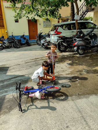 Banaglore, India- February 20th 2021; Stock photo of 7 to 9 year old Indian boy helping and teaching his 3 to 5 year old younger brother how to ride bicycle on road at Banglore , Karnataka, India.のeditorial素材