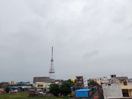 Stock photo of top view of cityscape. Tall mobile network tower installed outskirts of the...