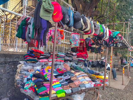 Kolhapur, India- December 3rd 2020; Stock photo of colorful woolen caps, regular caps, hat, socks and hand gloves hanging at street garment shop or street shop during winter season at Kolhapur,のeditorial素材