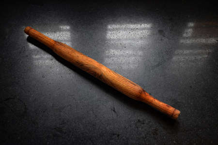 Stock photo of brown color wooden rolling pin kept on black granite kitchen slab at Bnaglore, Karnataka, India. picture captured under natural light. focus on object.の写真素材