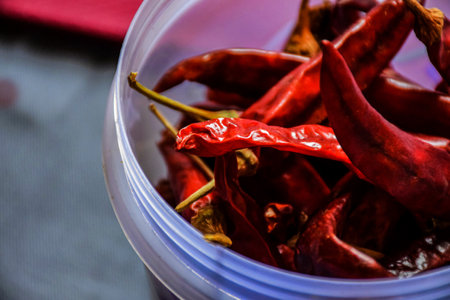 Stock photo of dry and hot red chilies kept in transparent plastic container on blue background. Picture captured under bright light at Bnaglore, Karnataka, India. organic food. selective focus.の写真素材