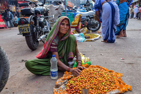 Tuljapur, India- December 19th 2019; Stock photo of 60 to 70 aged Indian grandma or old women wearing saree , selling jujube fruit on the street of city market area. Picture captured at Tuljapur.のeditorial素材
