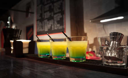three glasses of cocktails are on the barの写真素材