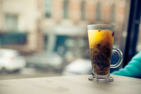 transparent cup with sea-buckthorn tea stands on a wooden table in a cafeの写真素材