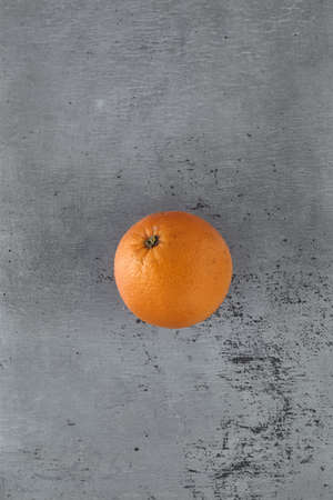 A whole fresh orange on a grated tin backgroundの写真素材