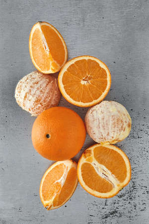 Whole, peeled and cut in half in different ways oranges on a tin backgroundの写真素材