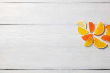 Marmalade in the form of orange slices yellow and orange on the background of a light wooden tableの写真素材