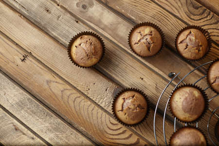 Cupcakes in brown paper form on an iron stand on a wooden tableの写真素材