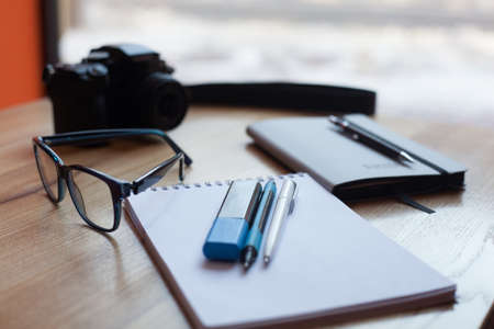 Camera, coffee, diary and pens on a wooden table in the coffee shop in front of the windowの写真素材