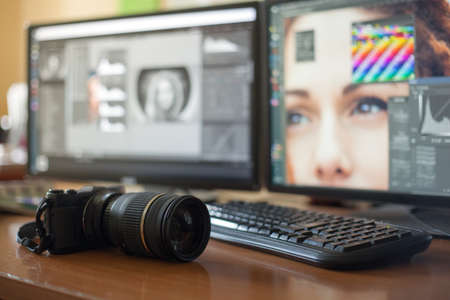 Desktop with two monitors, a keyboard, a camera, a diary, a palette for a designer, a retoucher, a photographer. With the image of the model on the monitors in special programs for retouching.の写真素材