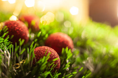 Christmas toy red shiny balls lie in a green tinsel in the background of a garlandの写真素材