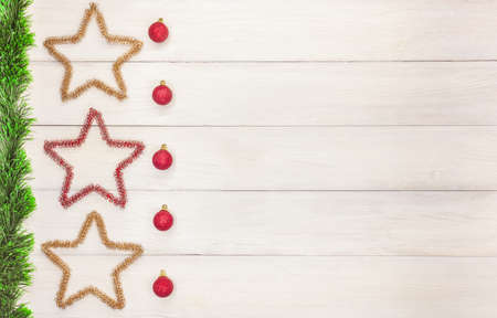 Christmas toys red balls and stars next to a green tinsel on a white wooden table