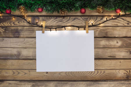 Christmas greeting on a white sheet hung on a garland with clothespins on a wooden background...
