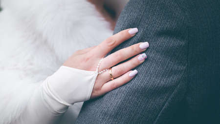 Bride's hand with a gold wedding ring on the hand of the groomの写真素材