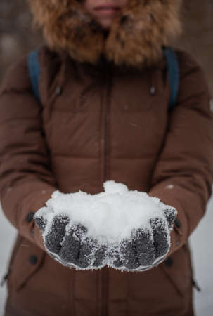 A girl holds a handful of snow in her hands, who are wearing gray gloves with a resouceの写真素材