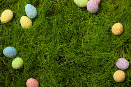 Easter Eggs of different colors on the lawn in the green grass in the middle place for textの写真素材