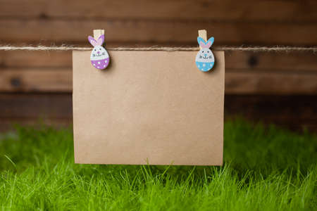 Kraft paper with space for text on clothespins in the form of an Easter bunny over green grassの写真素材