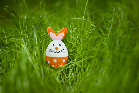 Easter egg little rabbit figurine on green grass