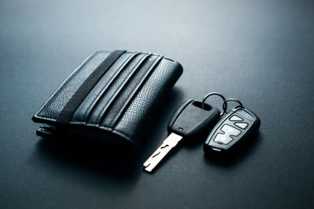 Black leather wallet with car key on a black background