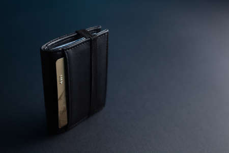 Black leather wallet with a gold credit card on an isolated black backgroundの写真素材
