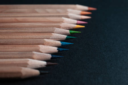Sharpened pencils of different colors made of light wood isolated on black background.の写真素材