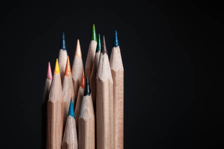 Sharpened pencils of different colors made of light wood isolated on black background.の写真素材