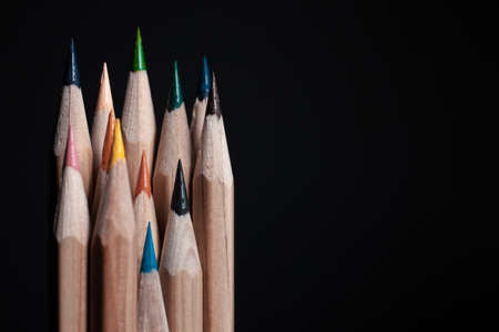 Sharpened pencils of different colors made of light wood isolated on black background.の写真素材