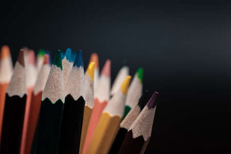 Sharpened pencils of different colors made of light wood isolated on black background.の写真素材