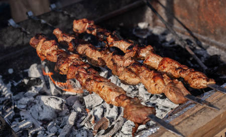 Meat on a skewer is fried on hot charcoal on an iron barbecue.の写真素材