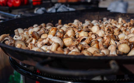 Lots of fried champignons in a large cast-iron skillet in the open airの写真素材