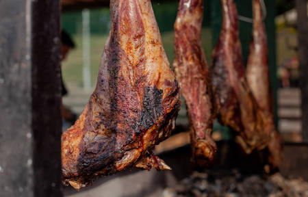 Marinated pork leg suspended above the grill is fried on hot coalsの写真素材